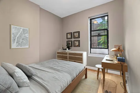 a bedroom with a bed a bookshelf a desk and chair