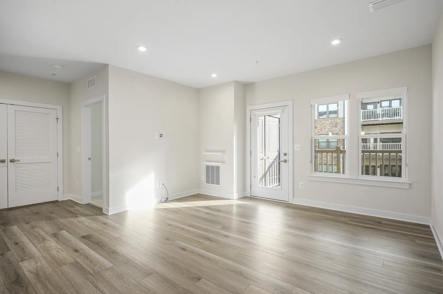a view of an empty room with wooden floor and windows
