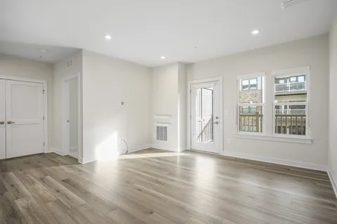 a view of an empty room with wooden floor and windows