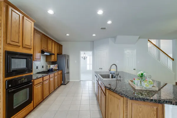 a kitchen with stainless steel appliances granite countertop a refrigerator sink and wooden cabinets