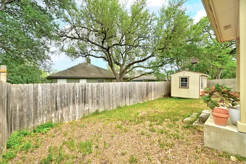 a backyard of a house with a table and chair under an umbrella