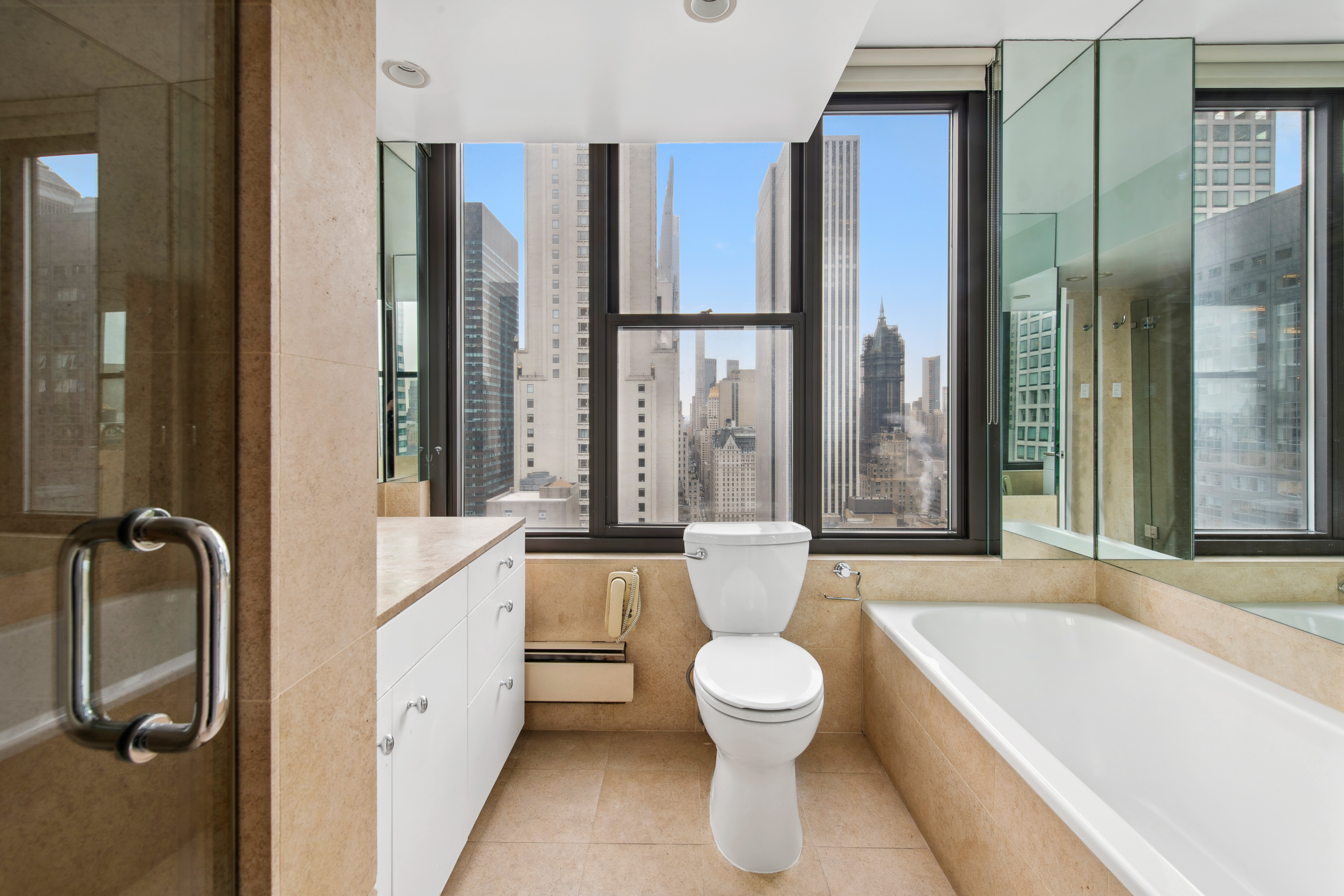 117 East 57th Street, Unit 35D Manhattan, NY 10022 - Photo 16 of 30 a bathroom with a white bath tub a mirror and a shower