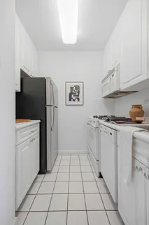 a kitchen with a refrigerator and white cabinets
