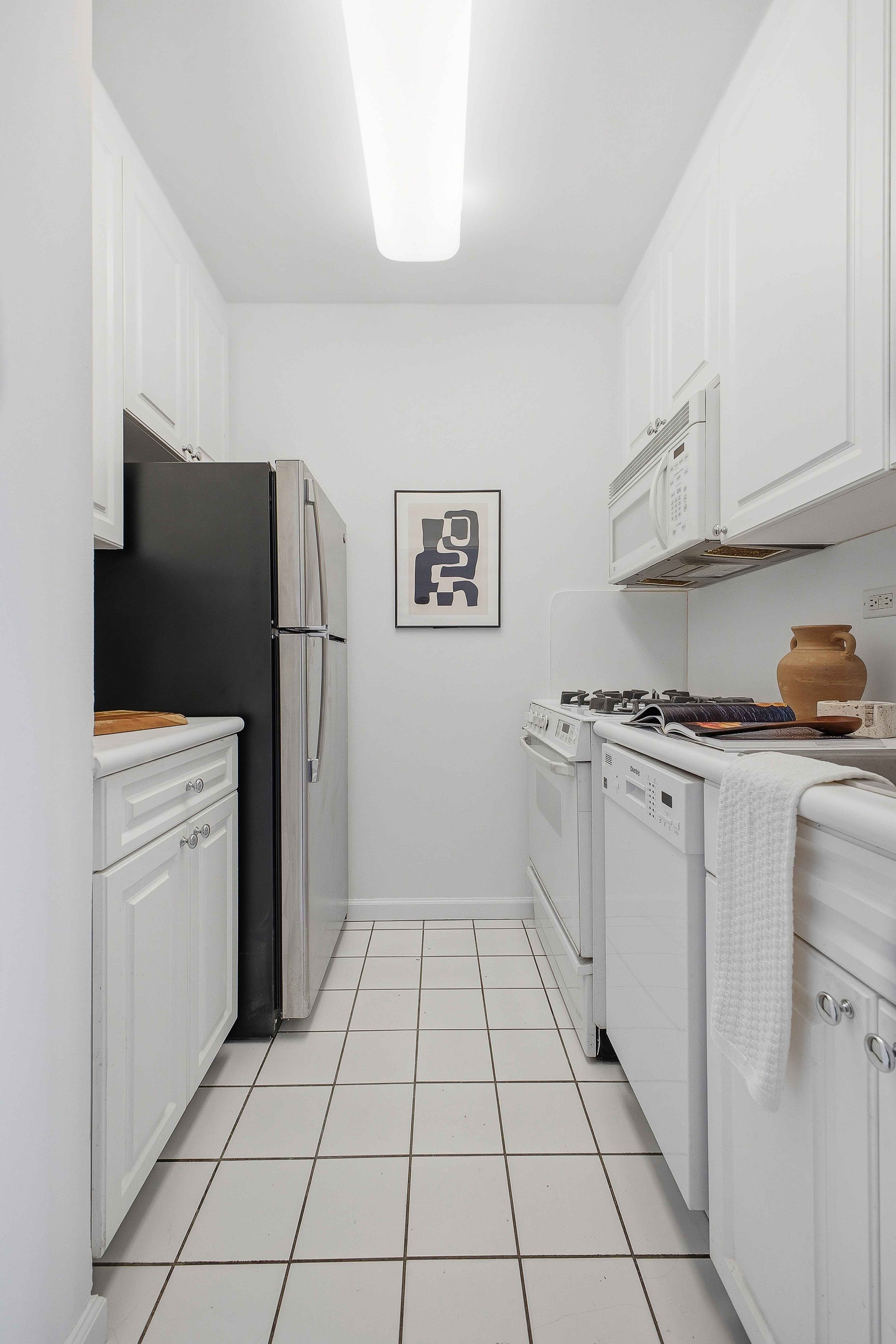 160 East 38th Street, Unit 26FG Manhattan, NY 10016 - Photo 13 of 23 a kitchen with a refrigerator and white cabinets