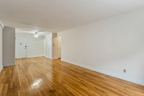 a view of an empty room with wooden floor and a window