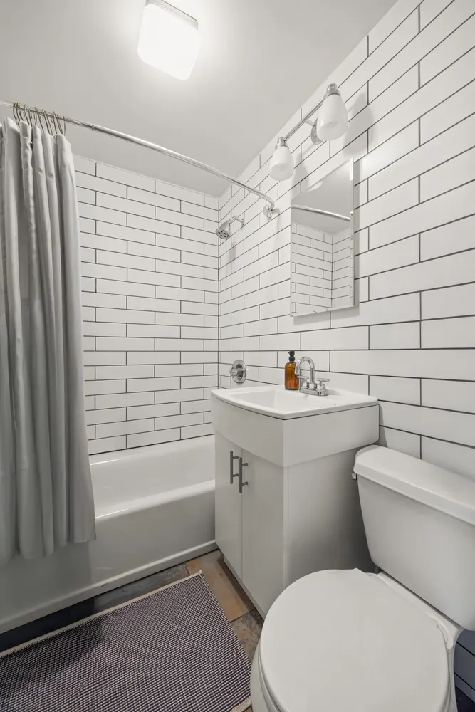 a bathroom with a toilet a sink a mirror and shower