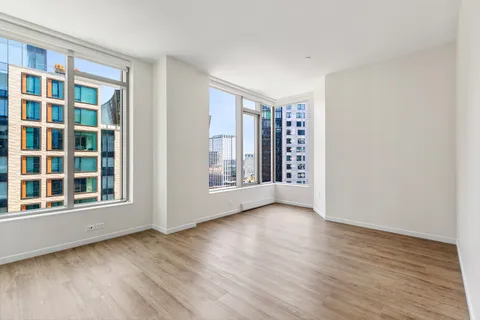 a view of an empty room with a window and wooden floor