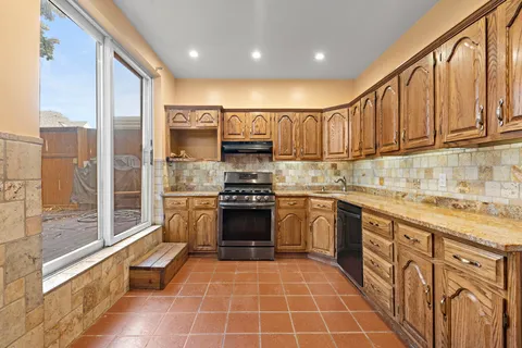 a kitchen with stainless steel appliances granite countertop a stove a sink and a refrigerator
