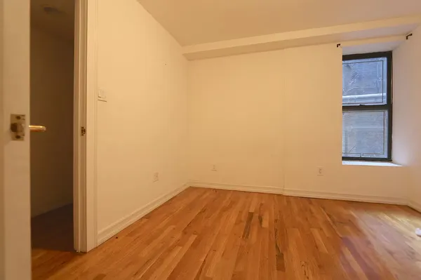 a view of a small space with wooden floor and a window