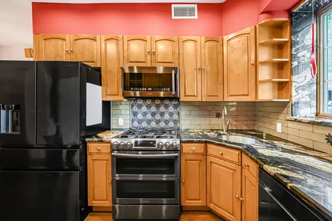 a kitchen with stainless steel appliances granite countertop a stove a refrigerator and a sink