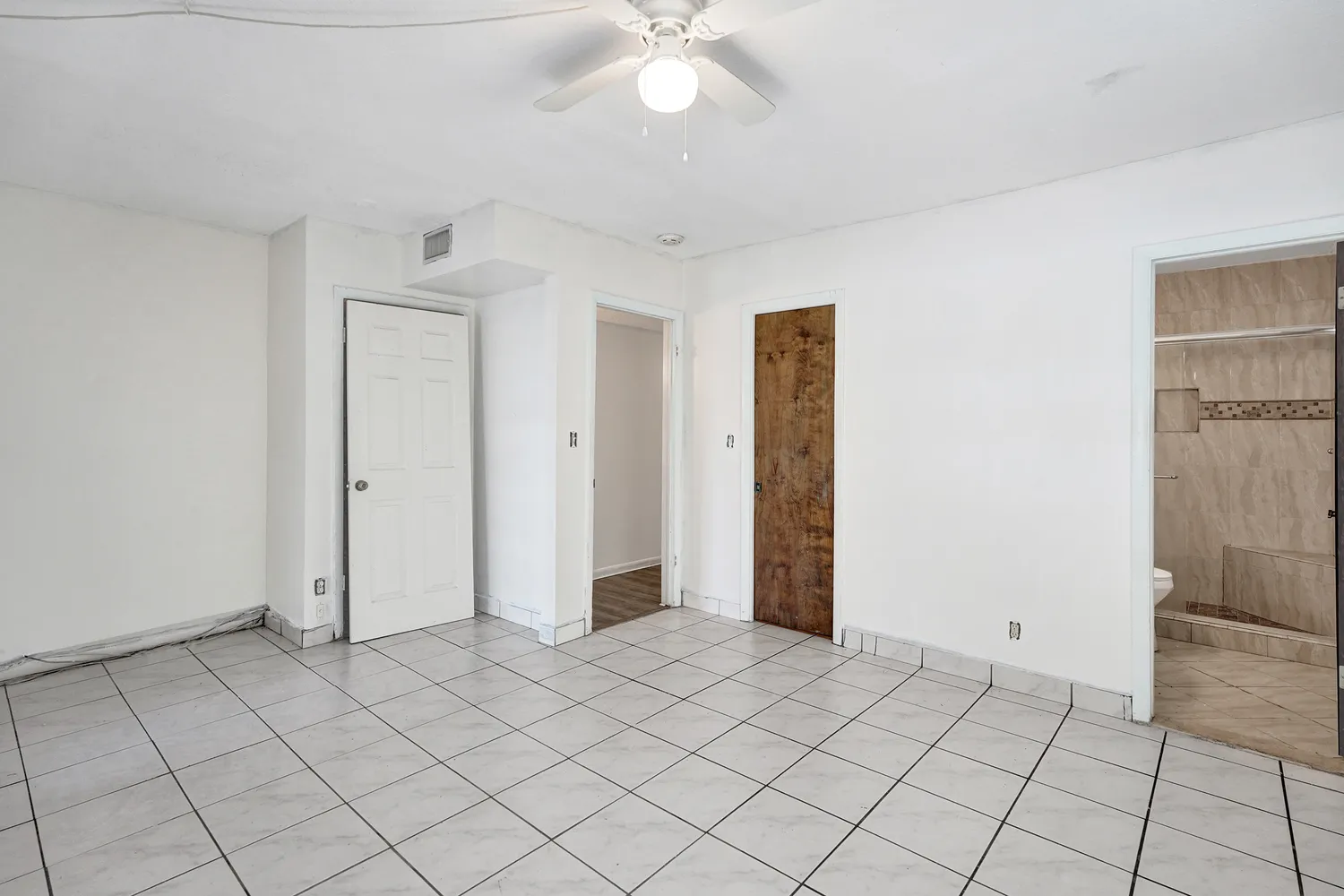 a view of a hallway with wooden floor and a bathroom