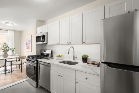 a kitchen with stainless steel appliances granite countertop a refrigerator sink and white cabinets