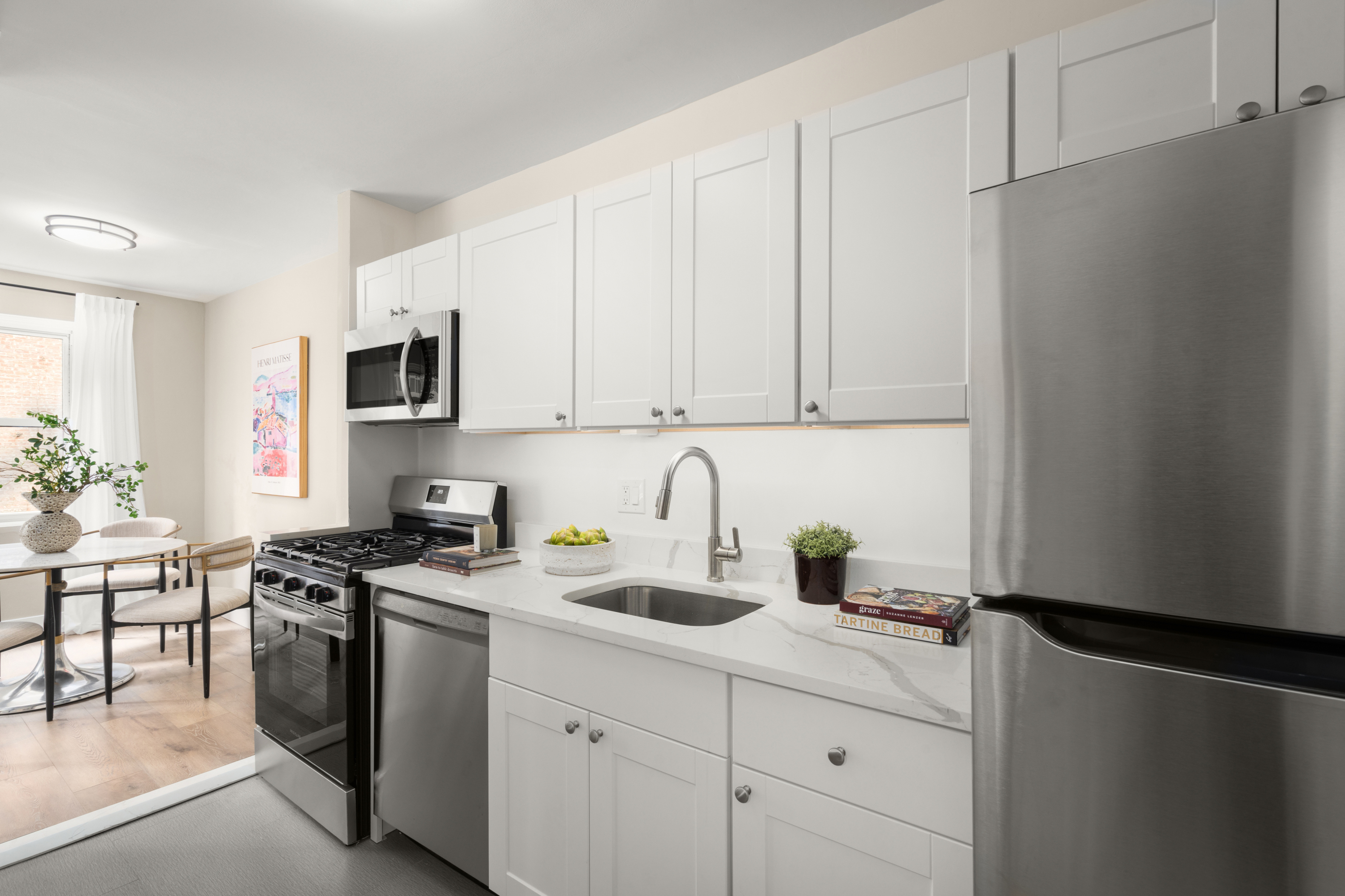 347 East 53rd Street, Unit 2C Manhattan, NY 10022 - Photo 8 of 18 a kitchen with stainless steel appliances granite countertop a refrigerator sink and white cabinets