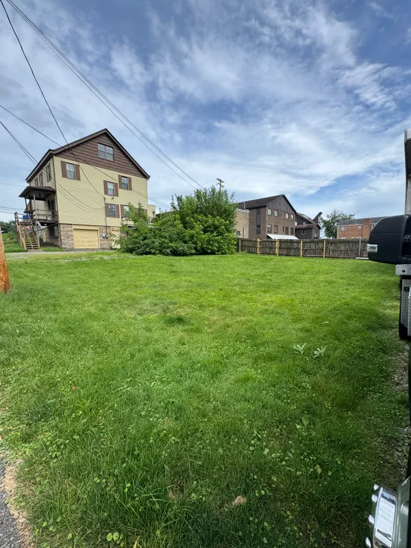 a view of a big house with a big yard and large trees