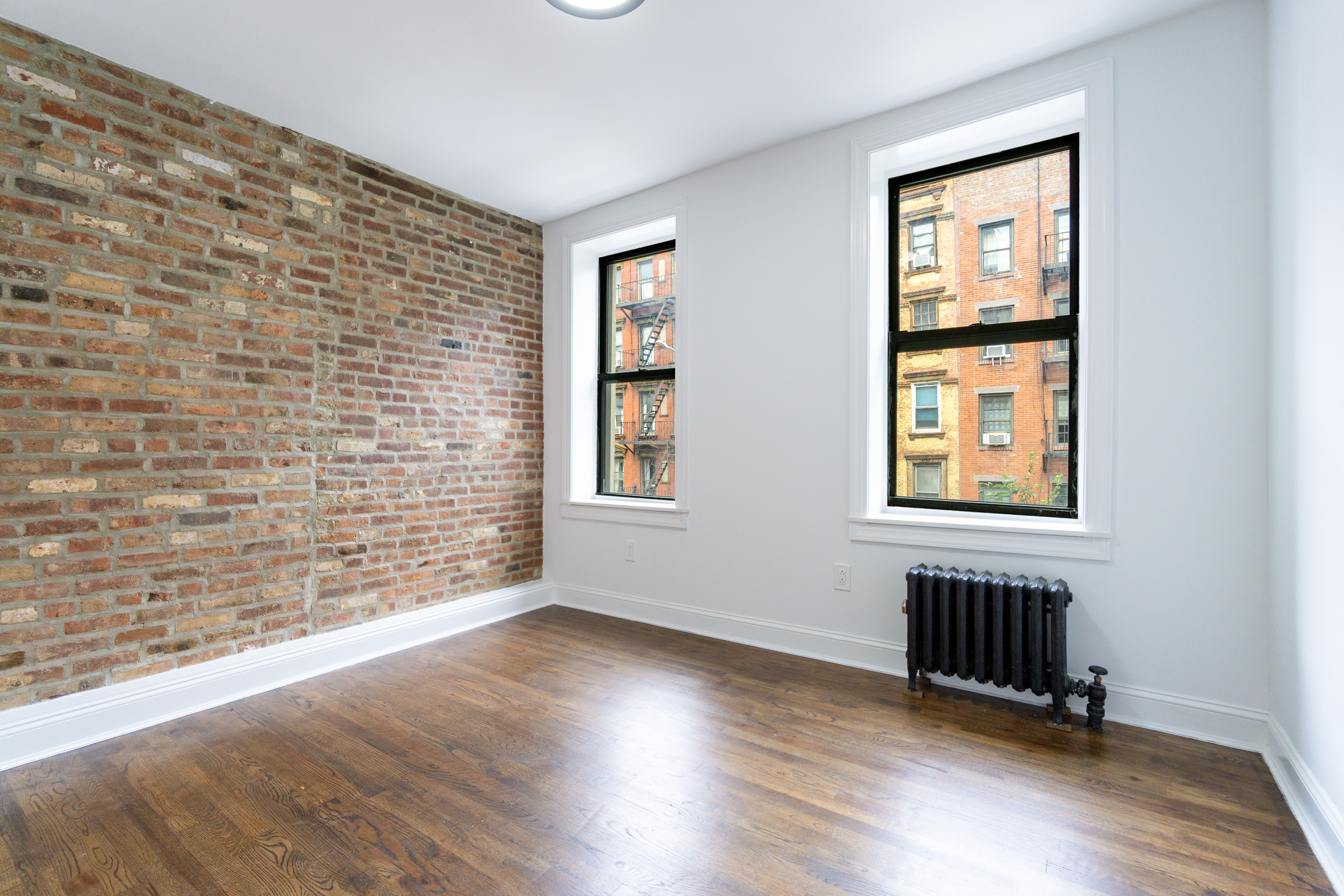342 East 6th Street, Unit 3 Manhattan, NY 10003 - Photo 8 of 13 an empty room with wooden floor and windows