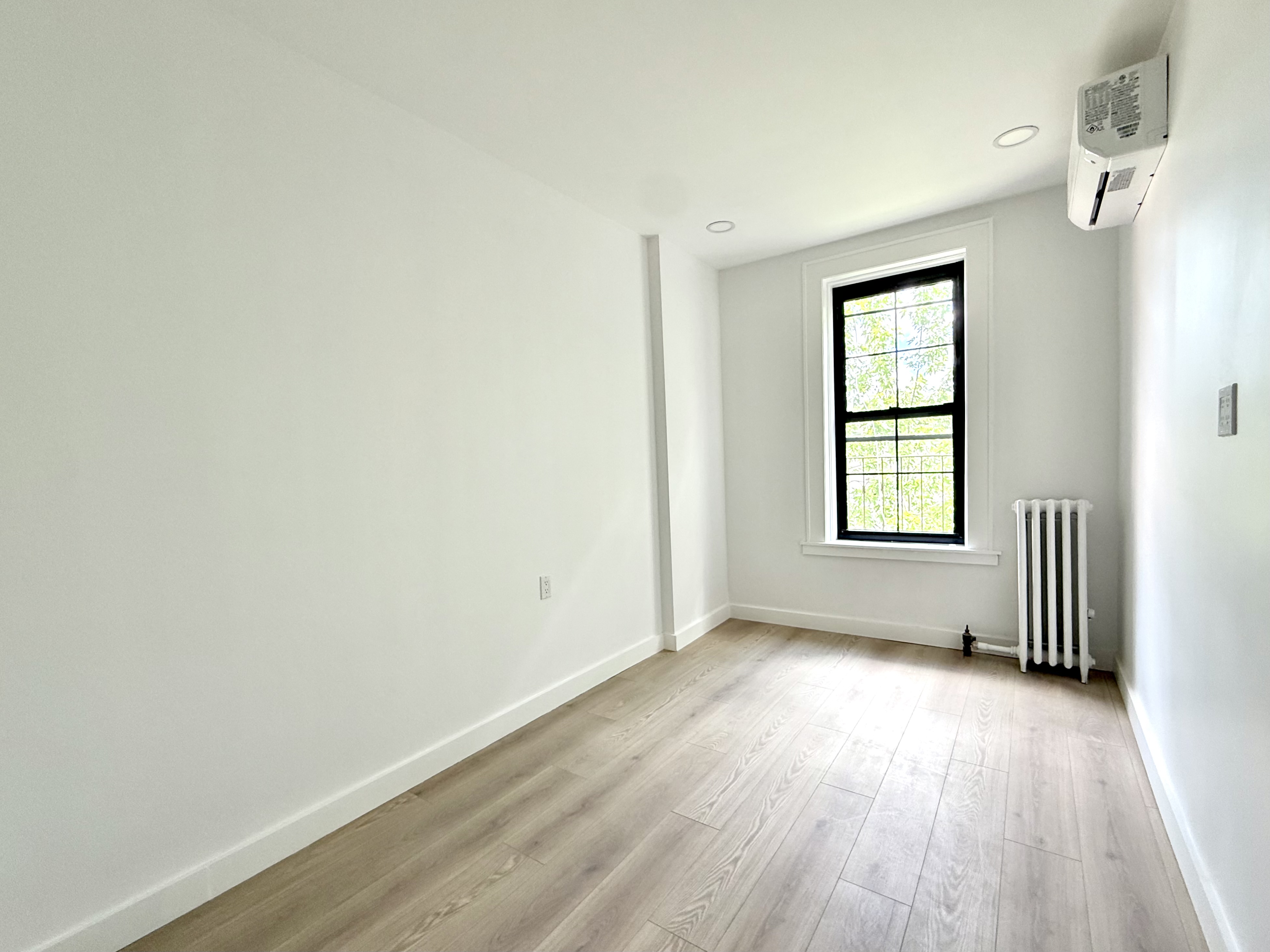 985 Rogers Avenue, Unit 3 Brooklyn, NY 11226 - Photo 7 of 10 an empty room with wooden floor and windows