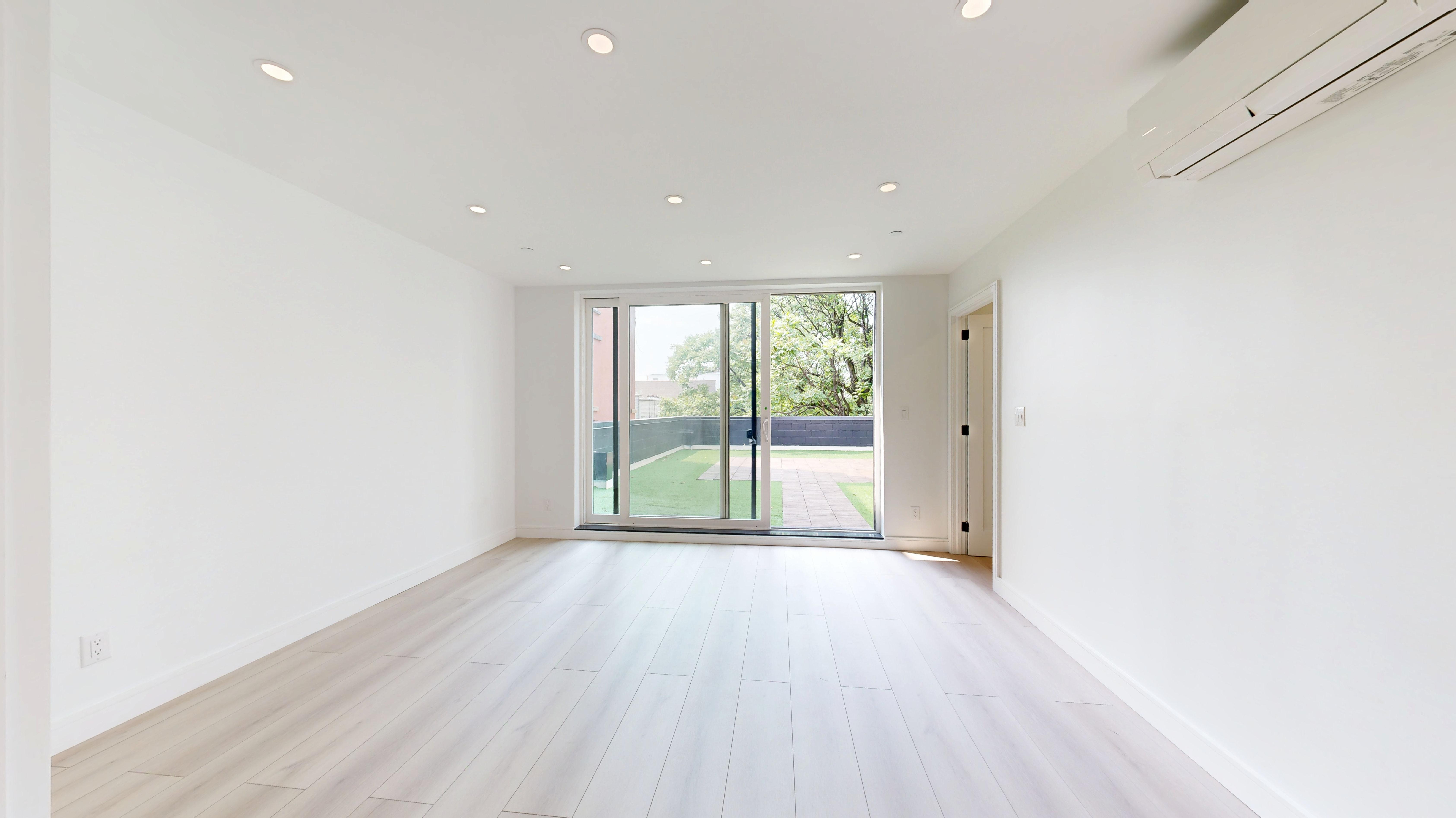 5614 3rd Avenue, Unit 2 Brooklyn, NY 11220 - Photo 9 of 12 an empty room with wooden floor and windows