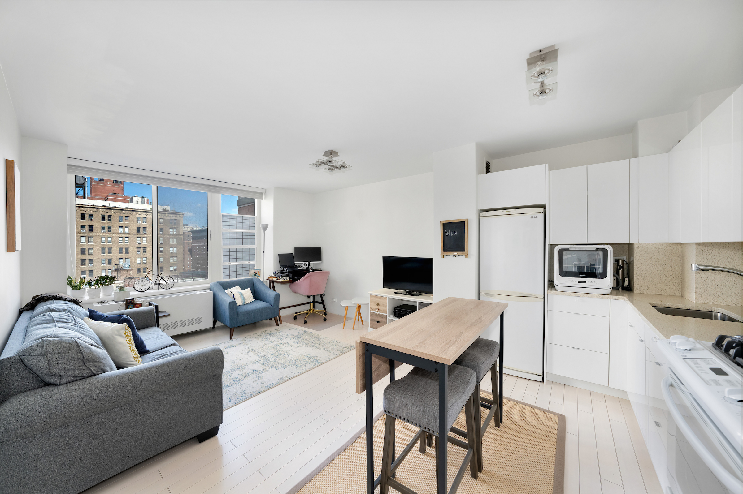 a living room with furniture a rug kitchen view and a window