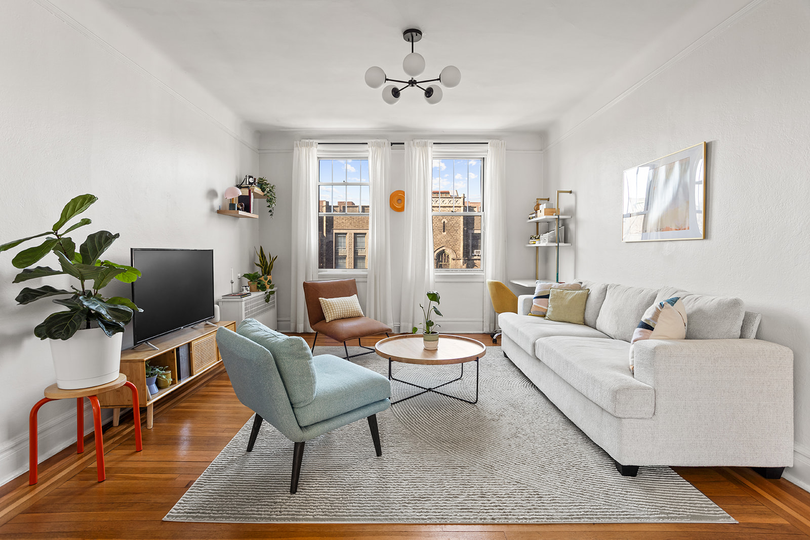 35-21 80th Street, Unit 52A Queens, NY 11372 - Photo 4 of 11 a living room with furniture a chandelier and a window