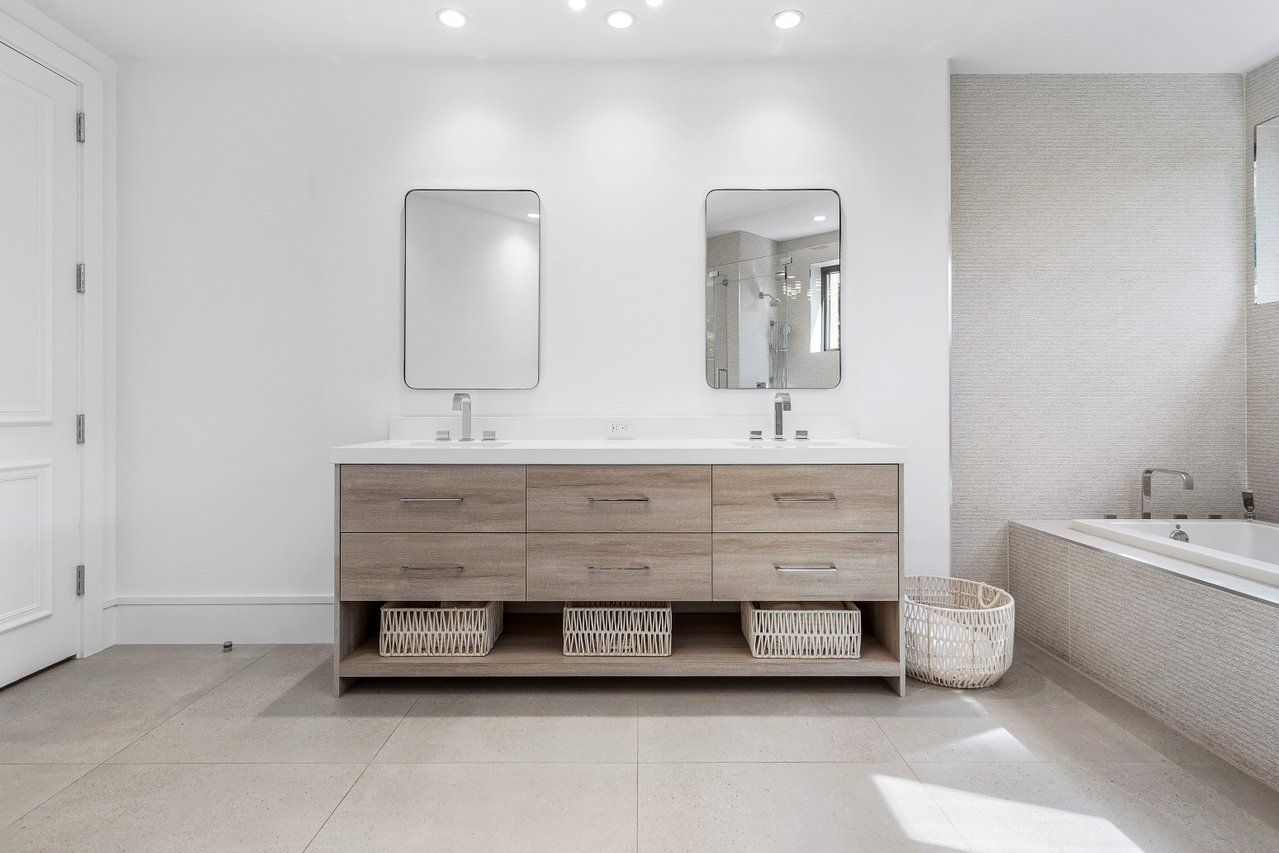 a bathroom with a double vanity sink a mirror and bathtub