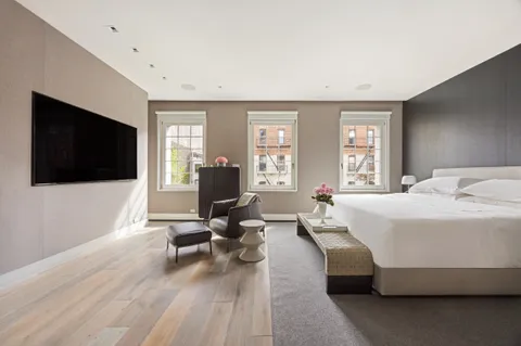 a spacious bedroom with a bed a couch and a large window