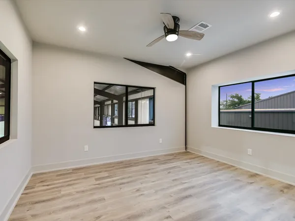 a view of an empty room with wooden floor and a window