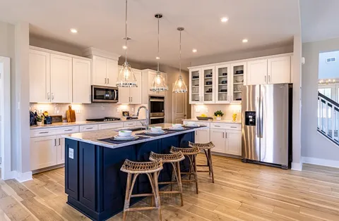 a kitchen with stainless steel appliances granite countertop a stove top oven a refrigerator a sink and a dining table with wooden floor