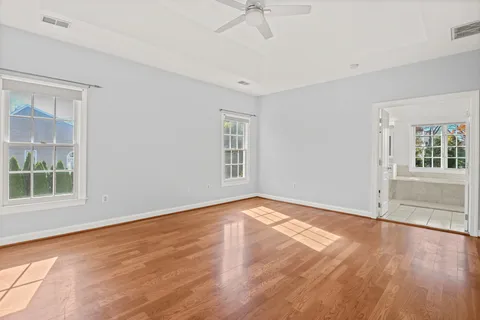 an empty room with wooden floor and windows