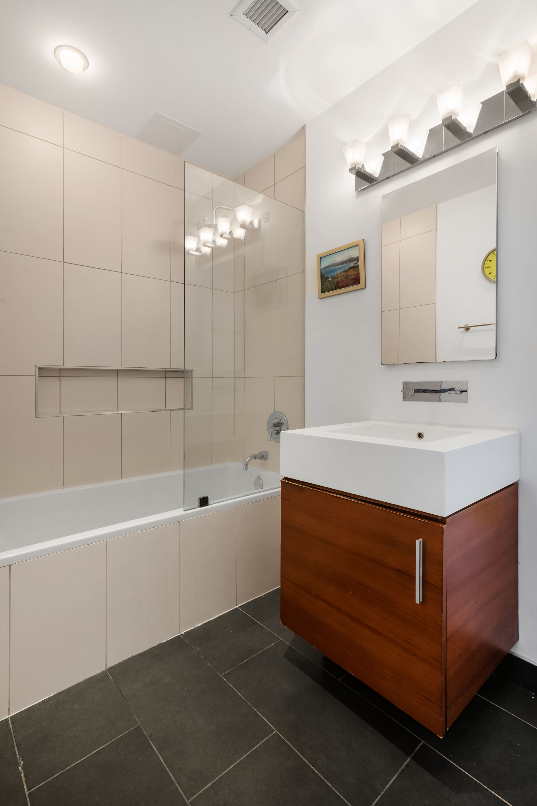 5-19 Borden Avenue, Unit 6C Queens, NY 11101 - Photo 6 of 11 a bathroom with a sink a mirror and a bathtub