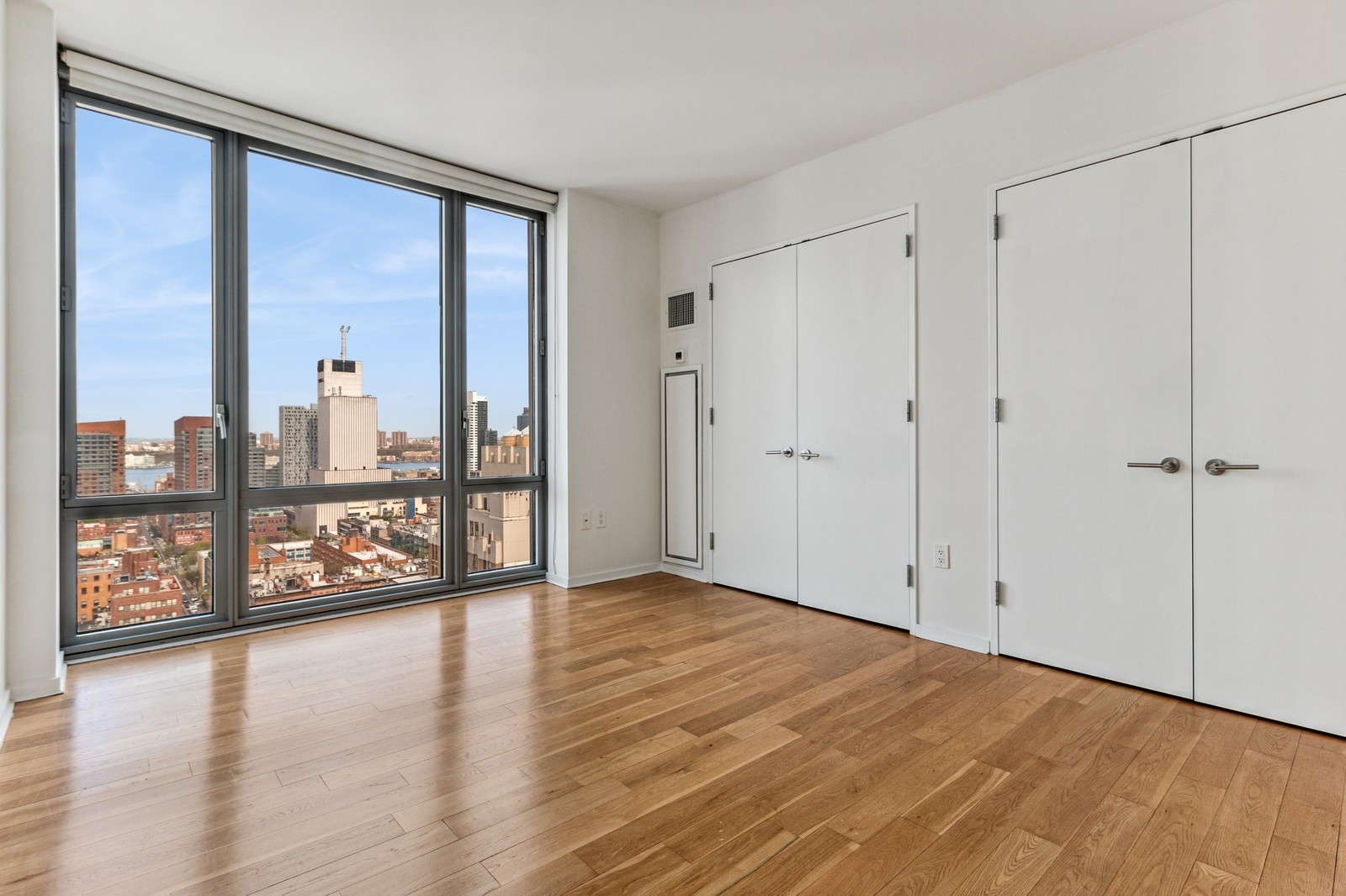 310 West 52nd Street, Unit 22H Manhattan, NY 10019 - Photo 8 of 12 a view of an empty room with window and wooden floor