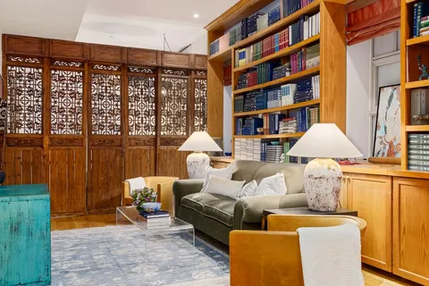 a living room with furniture a bookshelf and a large window