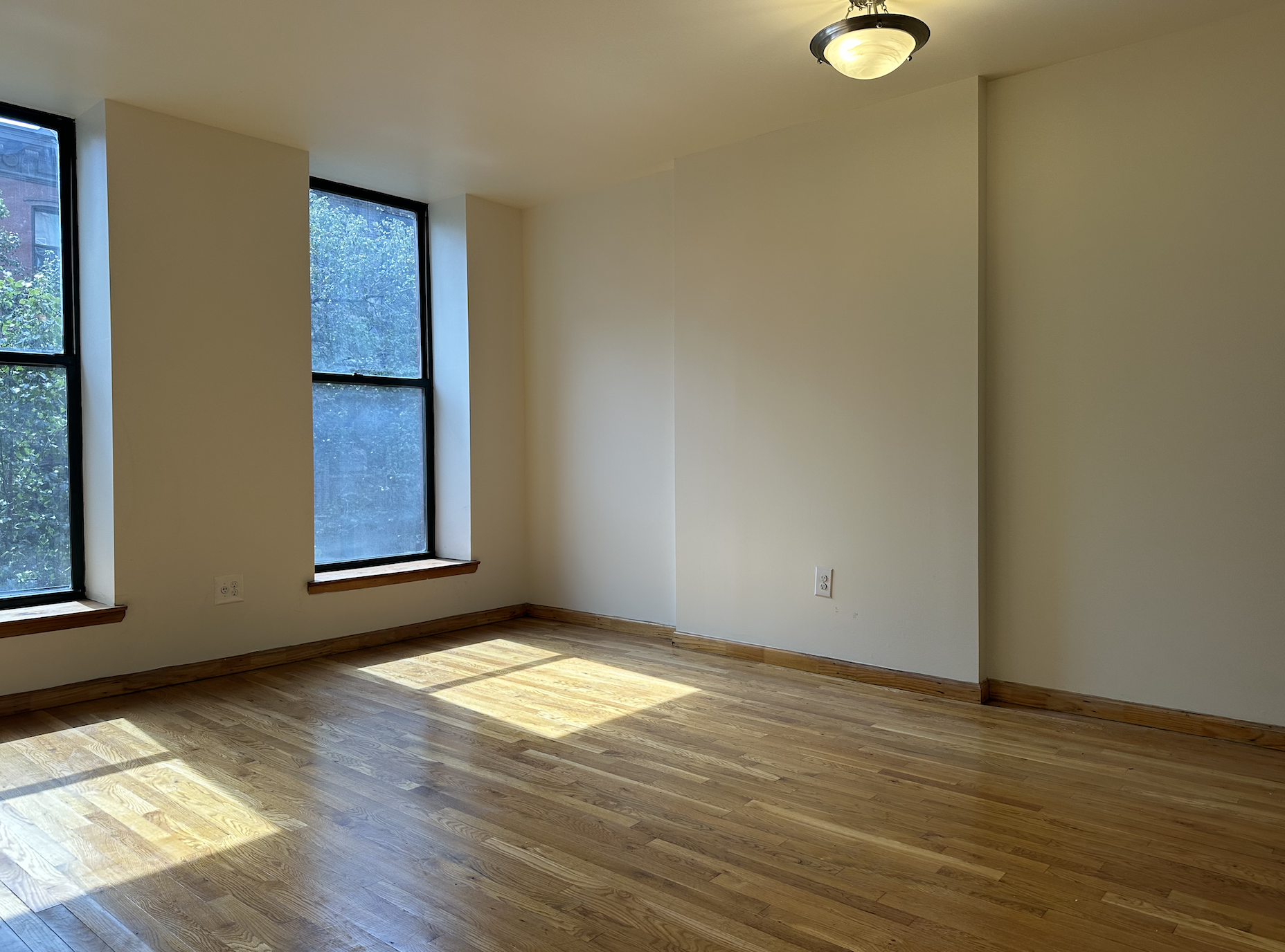 403 West 40th Street, Unit 2FE Manhattan, NY 10018 - Photo 3 of 12 an empty room with wooden floor and windows