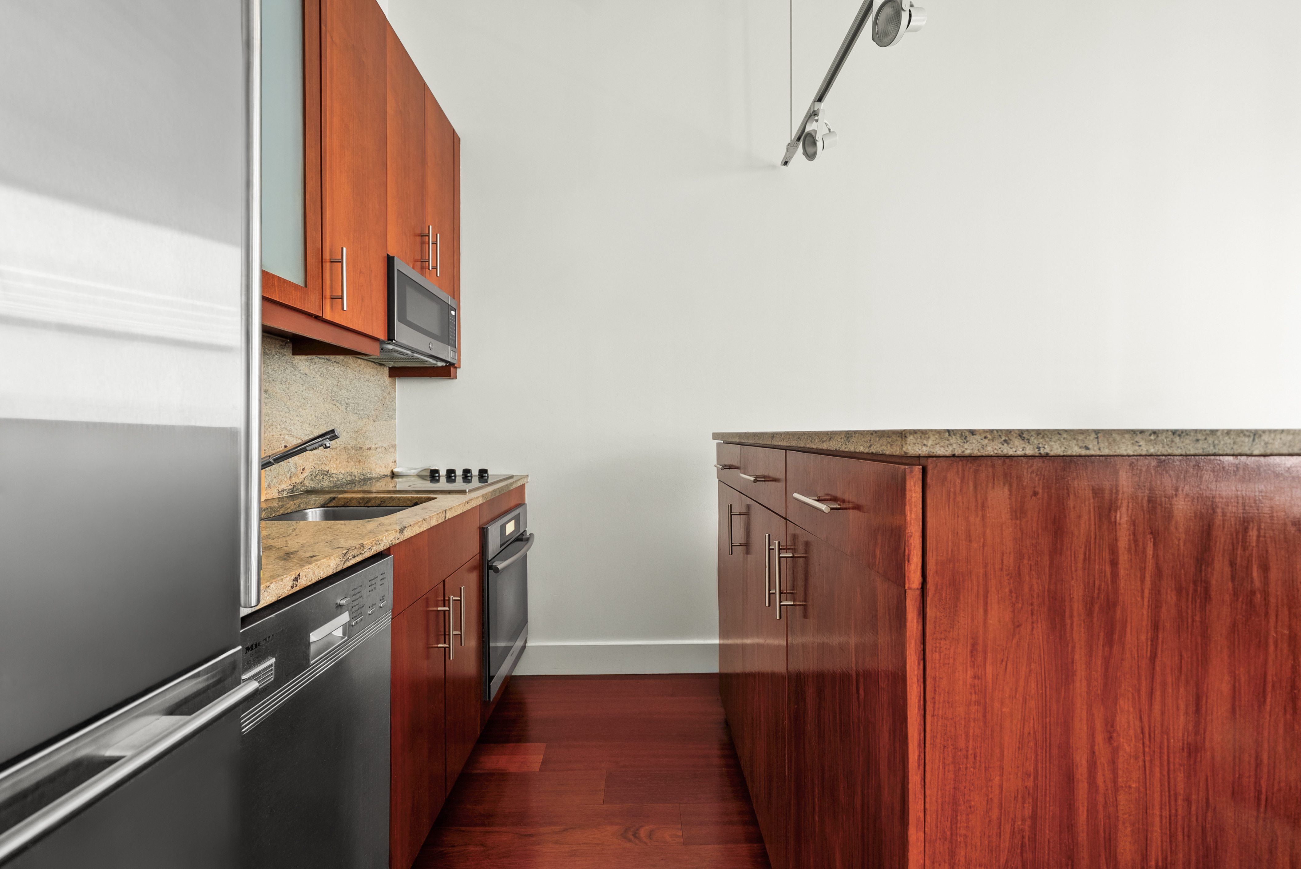 80 John Street, Unit 8H Manhattan, NY 10038 - Photo 3 of 6 a kitchen with granite countertop a sink cabinets and stainless steel appliances