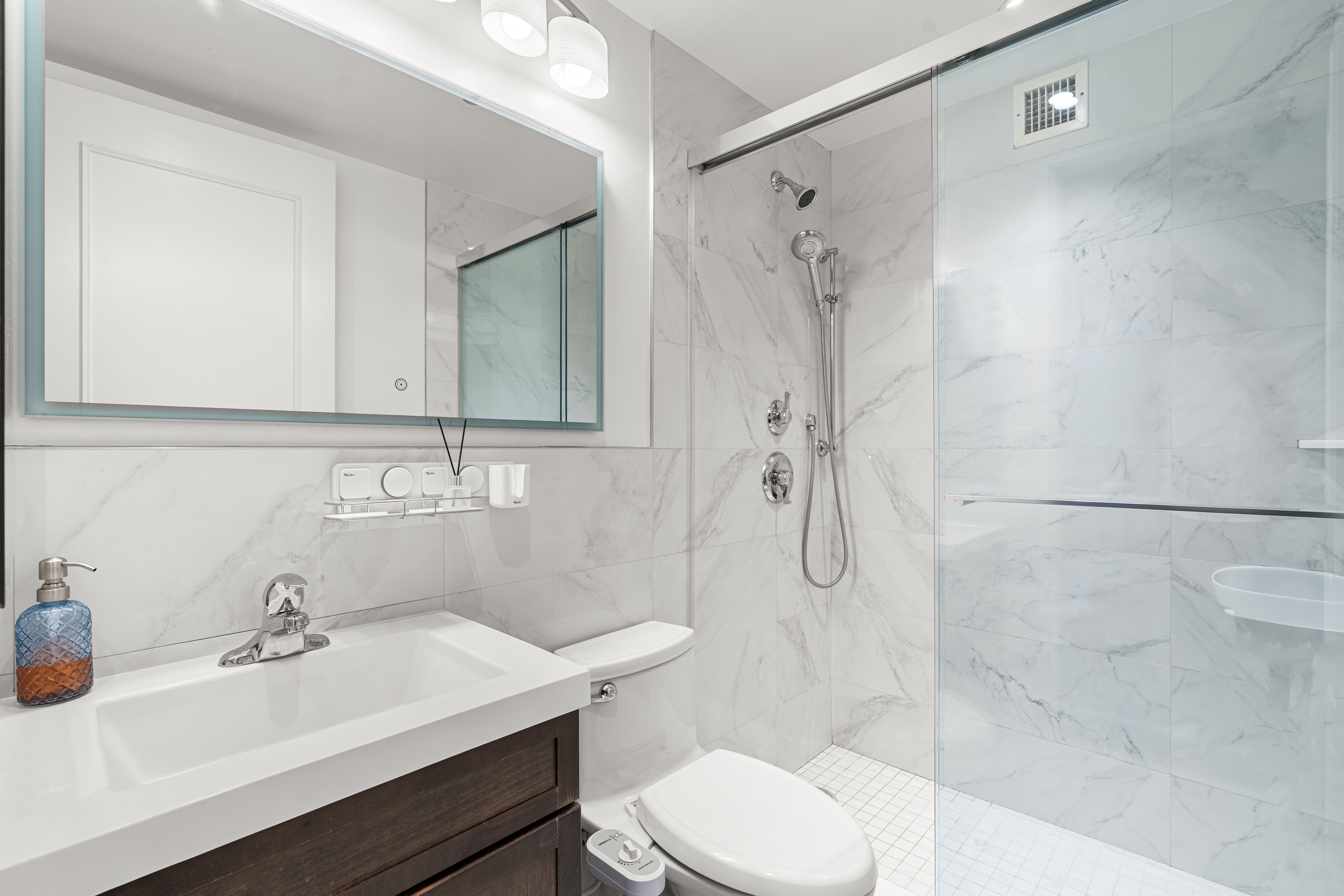 236 East 47th Street, Unit 17C Manhattan, NY 10017 - Photo 4 of 11 a bathroom with a sink toilet a mirror and shower