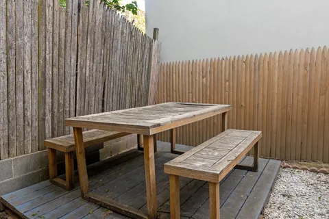 a balcony with wooden floor table and chairs