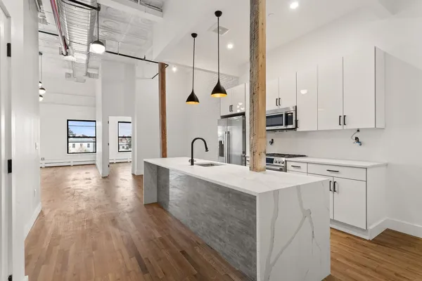 a kitchen with stainless steel appliances a sink dishwasher a refrigerator a stove and white cabinets with wooden floor