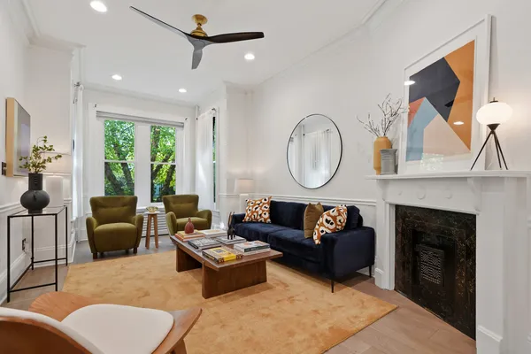 a living room with furniture a rug a fireplace and a large window