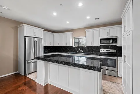 a kitchen with stainless steel appliances granite countertop a sink dishwasher and cabinets with wooden floor