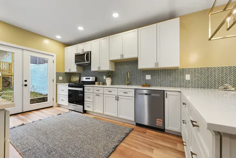 a kitchen with white cabinets and sink