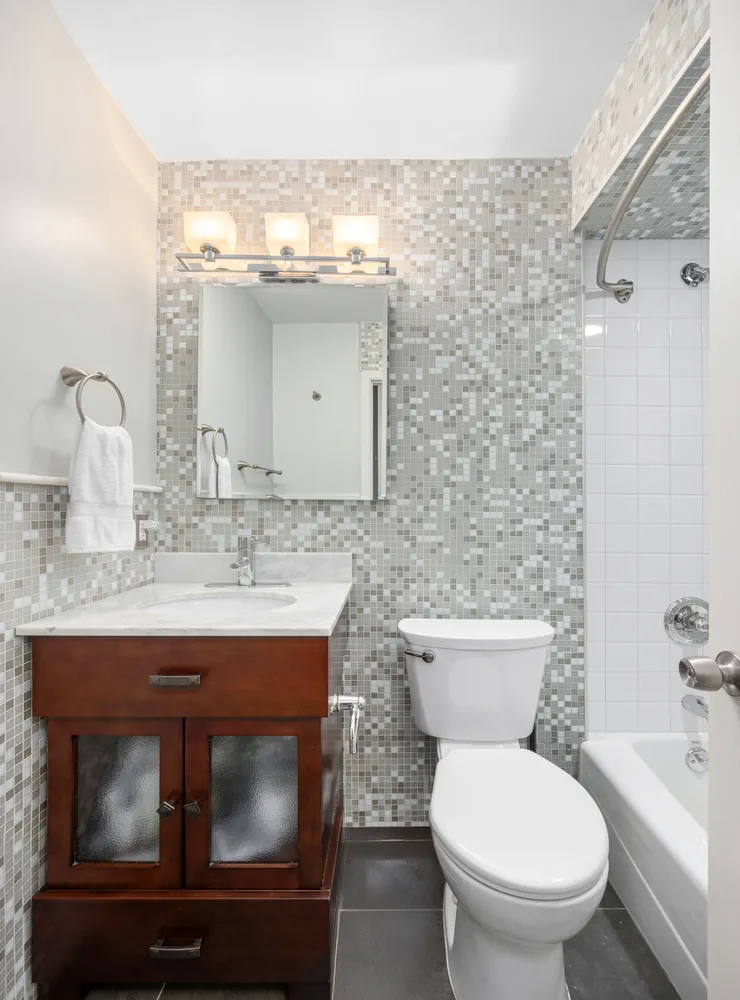 a bathroom with a granite countertop toilet sink and mirror
