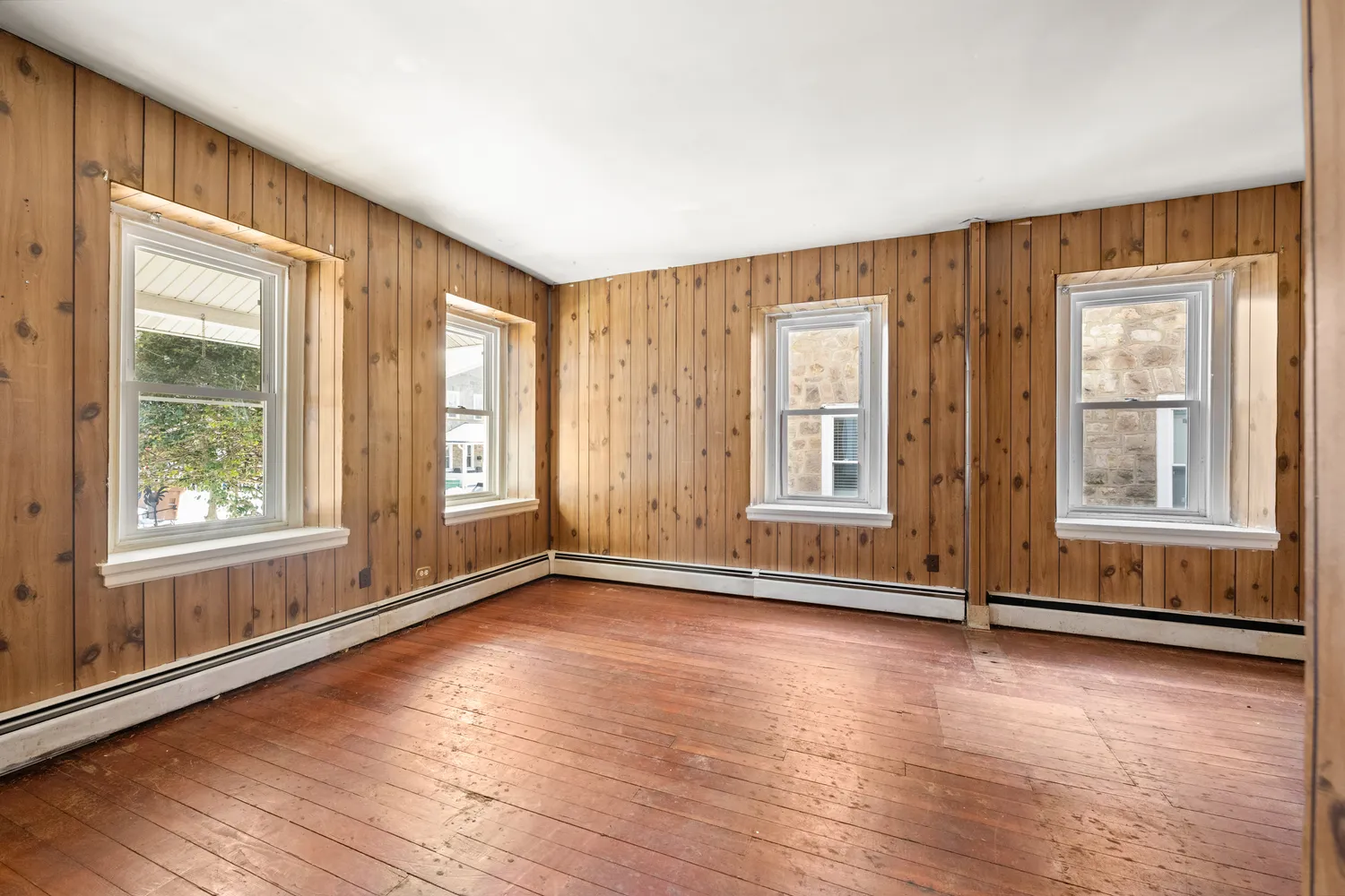 an empty room with wooden floor and windows