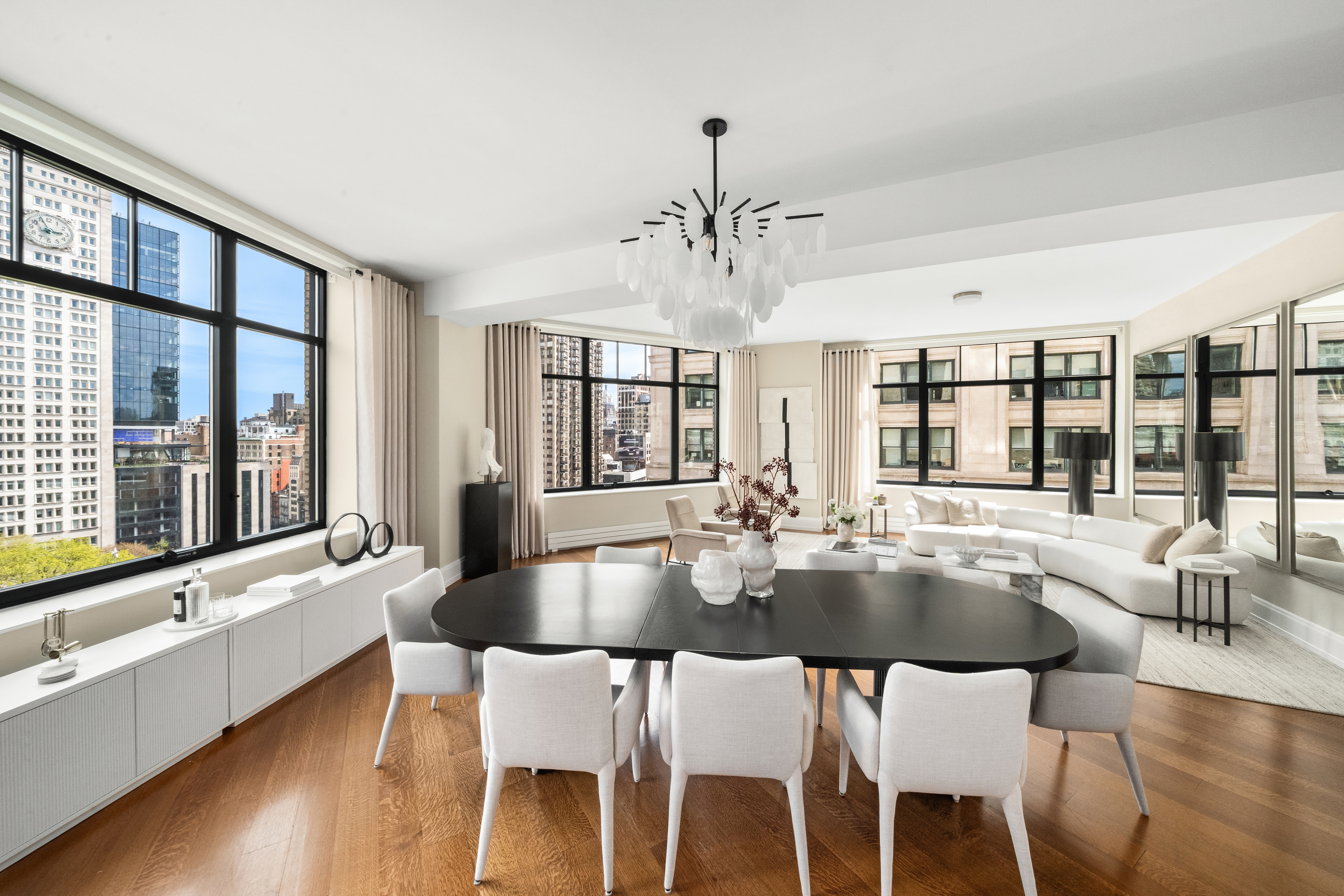 10 Madison Square West, Unit 12D Manhattan, NY 10010 - Photo 3 of 21 a dining room with wooden floor a chandelier a glass table and chairs