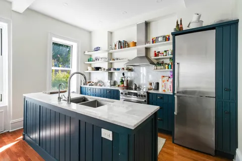 a kitchen with stainless steel appliances granite countertop a refrigerator a sink a stove and a dining table with wooden floor