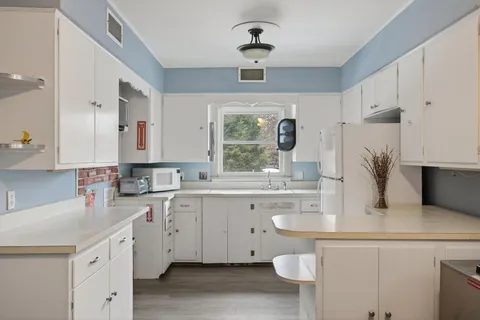 a kitchen with a sink a stove a refrigerator and white cabinets