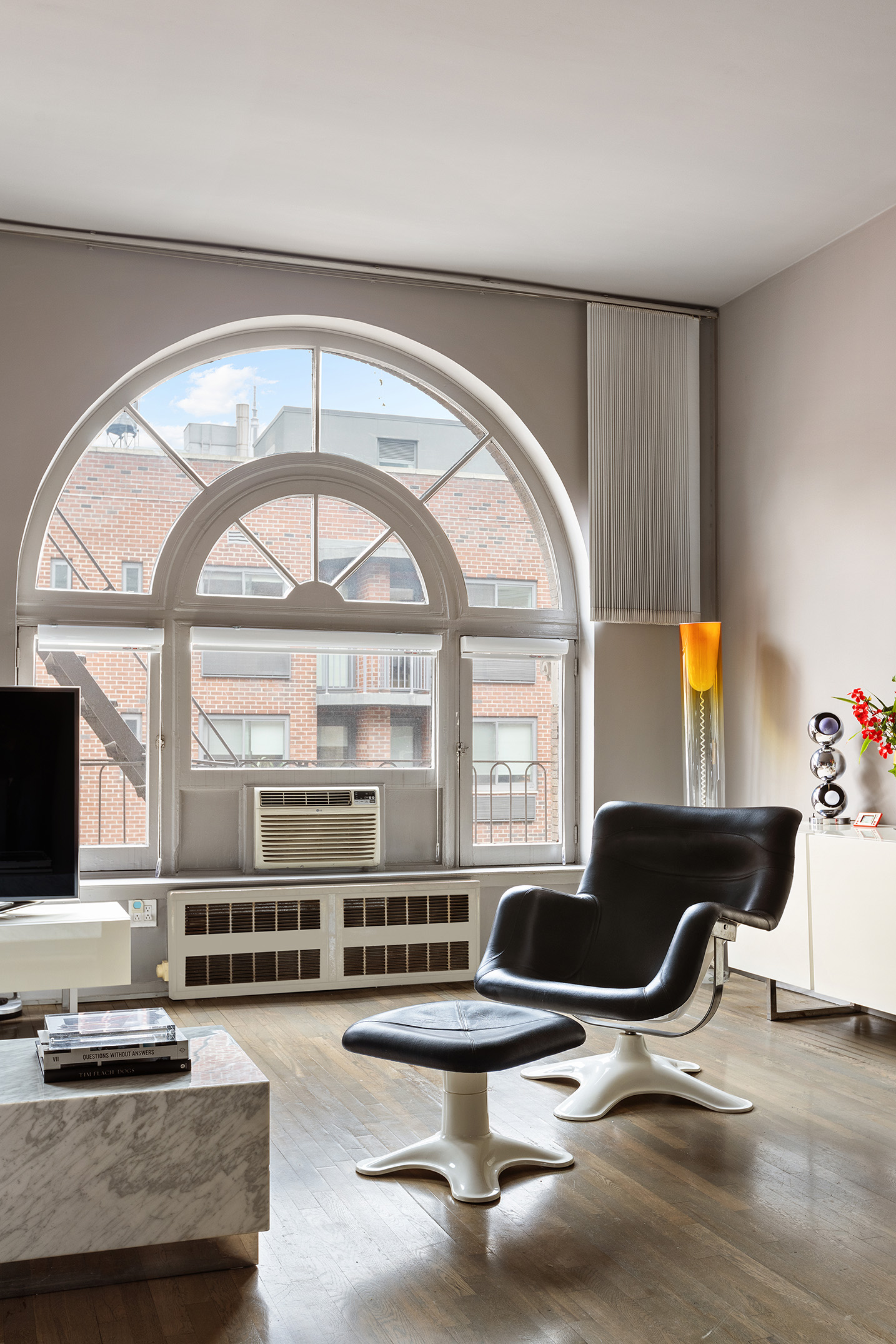 100 West 15th Street, Unit 4BC Manhattan, NY 10011 - Photo 3 of 9 a living room with couches a flat screen tv and kitchen view with a large window