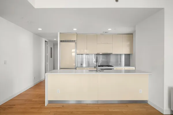a view of kitchen with stainless steel appliances granite countertop white cabinets and wooden floor