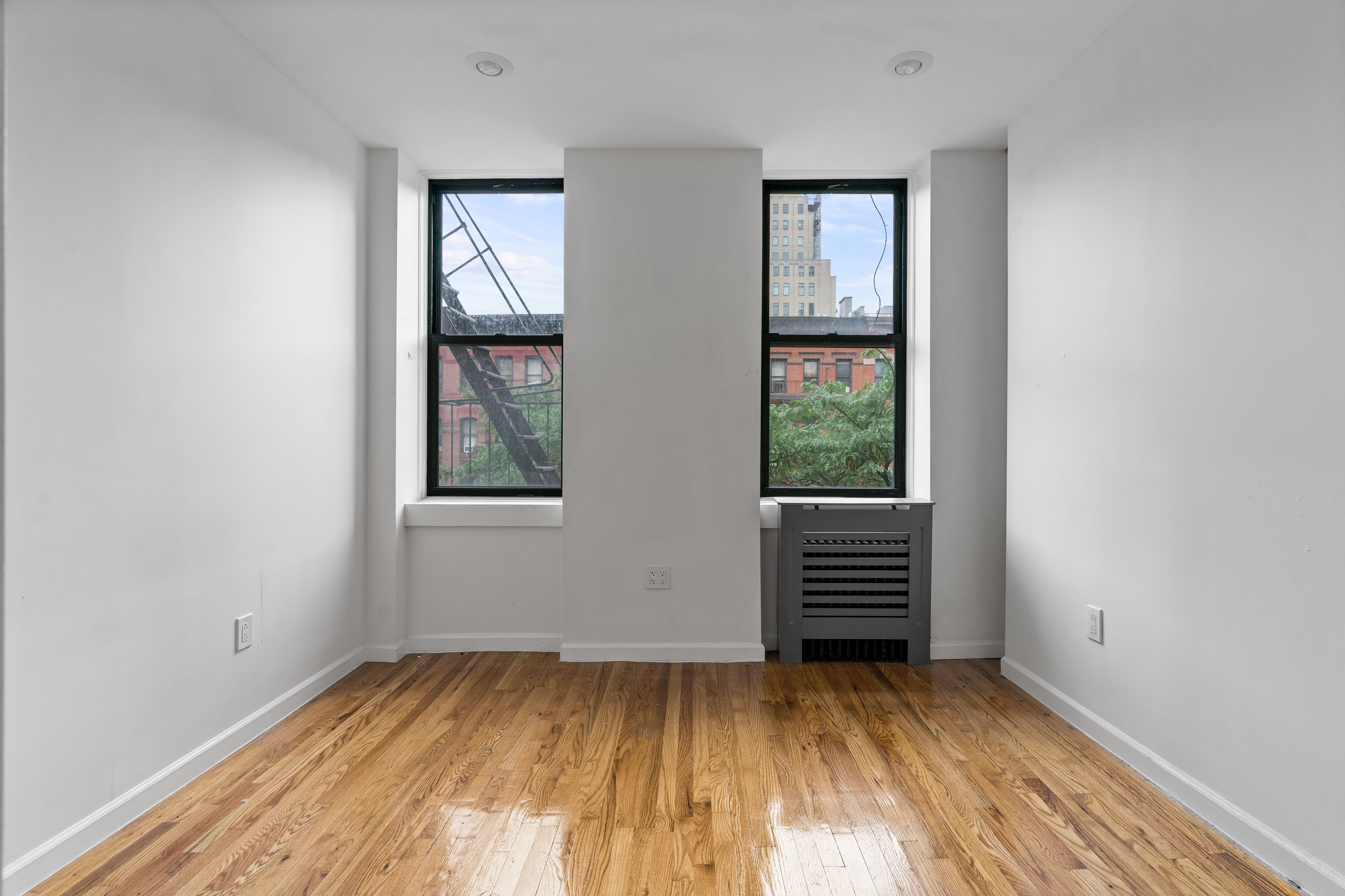 746 9th Avenue, Unit 4DF Manhattan, NY 10019 - Photo 4 of 13 an empty room with wooden floor and windows