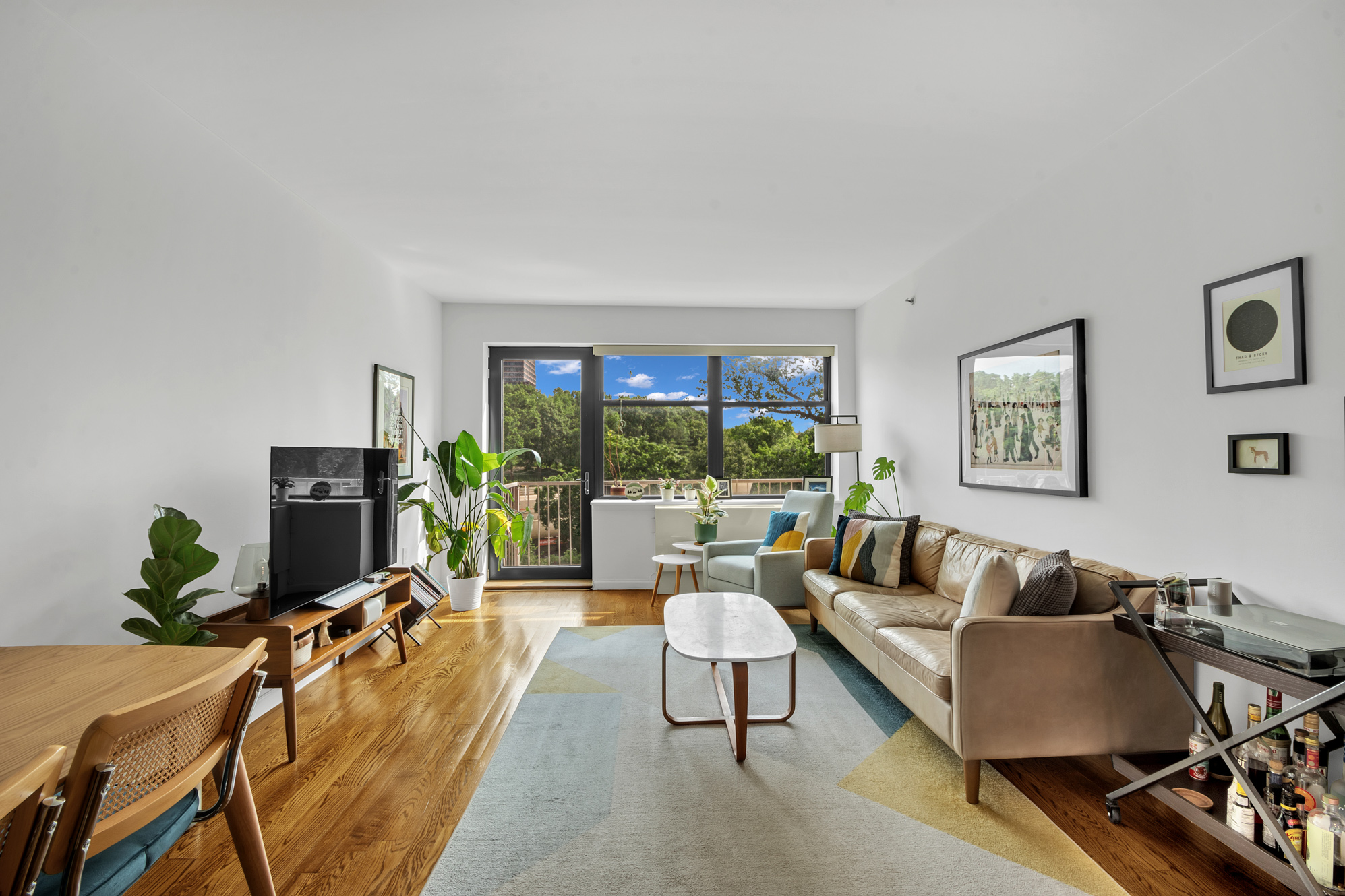 2002 5th Avenue, Unit 5B Manhattan, NY 10035 - Photo 2 of 7 a living room with furniture flat screen tv and a large window