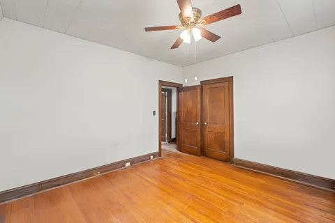 an empty room with chandelier fan and closet area