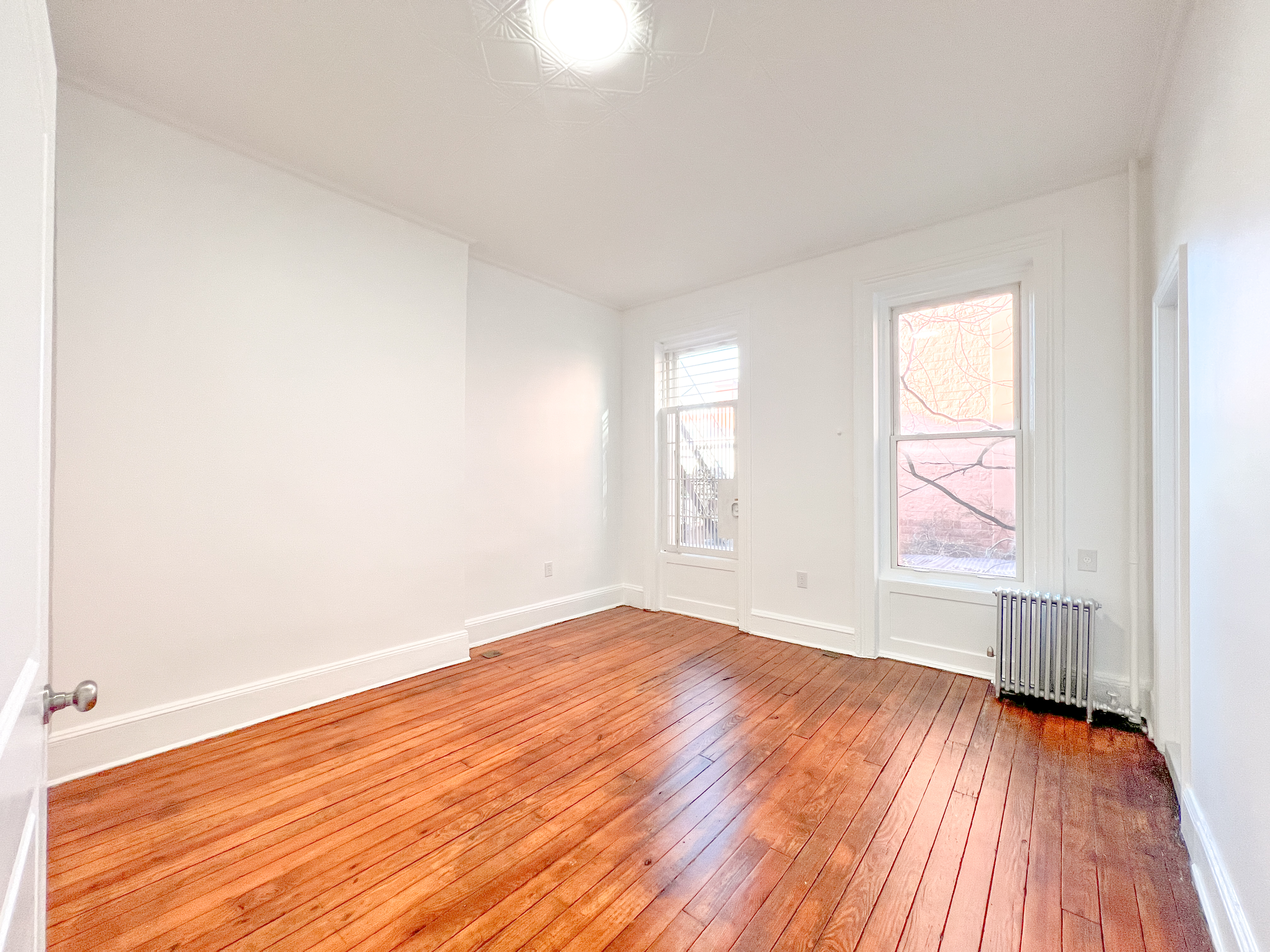 556 Vanderbilt Avenue, Unit 2 Brooklyn, NY 11238 - Photo 5 of 14 an empty room with wooden floor and windows